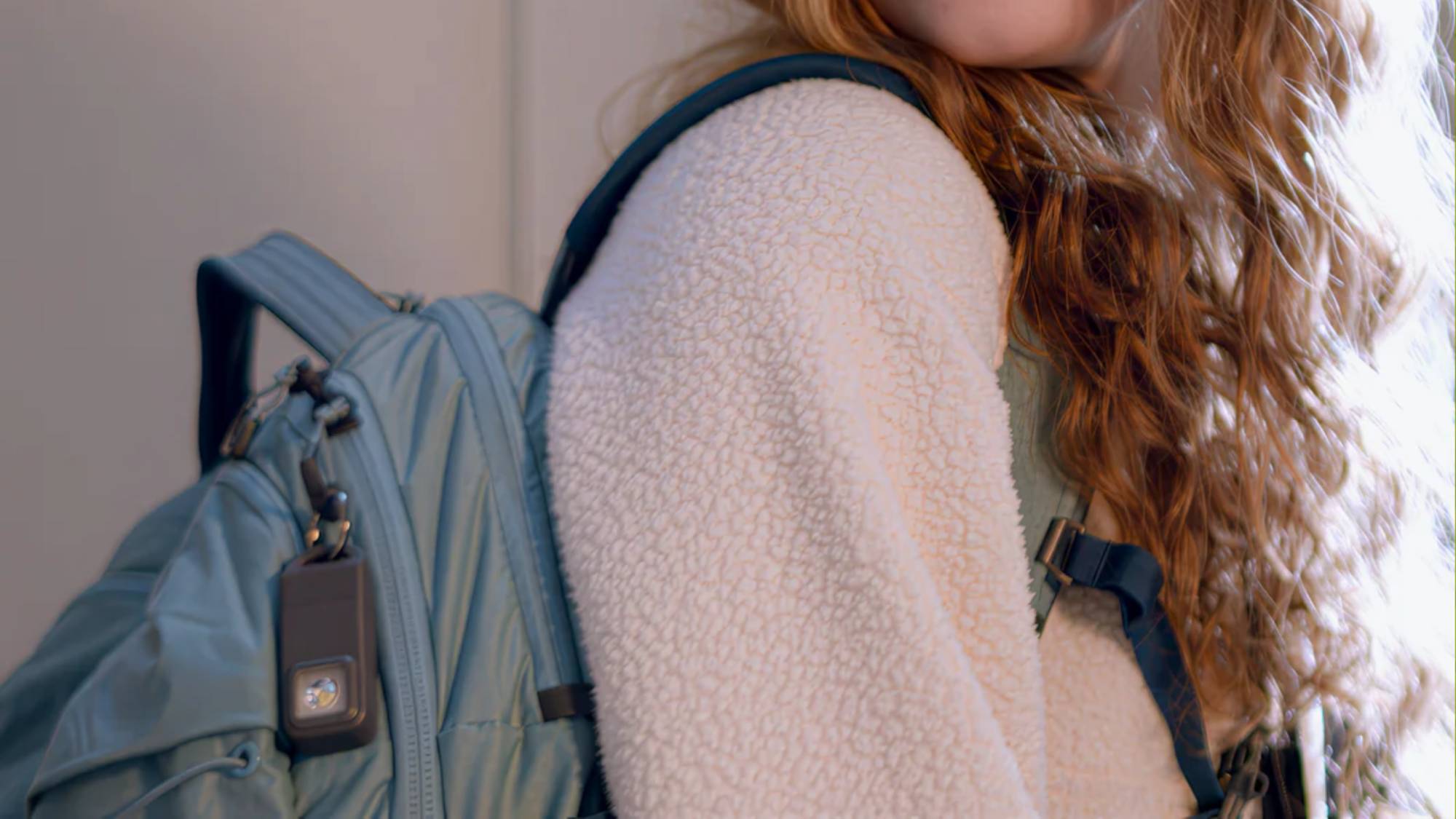 The Pebblebee Halo safety tracker clipped onto a student's backpack