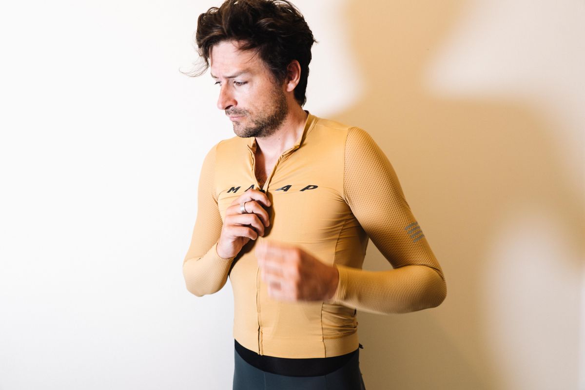 A white man in a tan jersey against a white wall