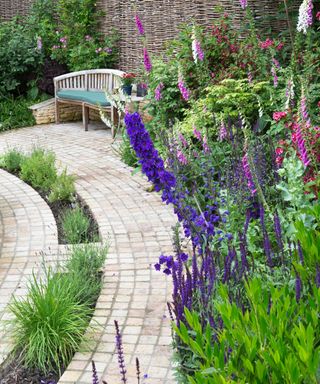 curved flower border and block paving in english cottage garden