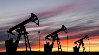Three oil pumps against a sunset background