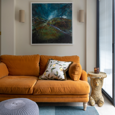 Orange sofa on blue rug and moneky shaped side table