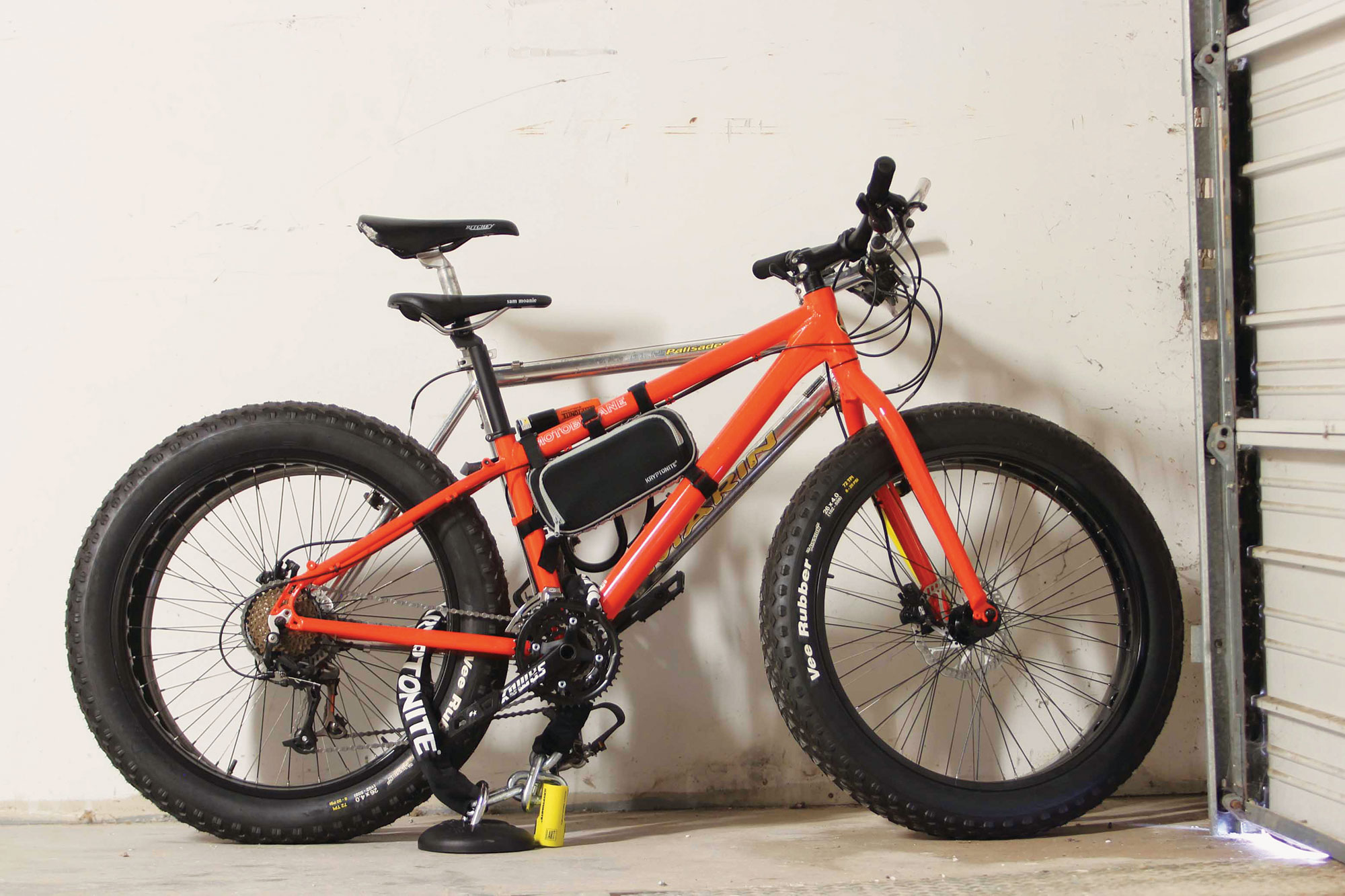 Two bikes secured to a ground anchor in a domestic garage