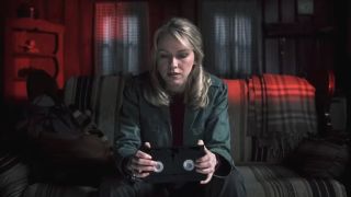 Naomi Watts sits in a dark hotel room while she stares at the tape in her hands in The Ring.