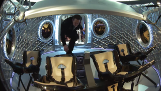SpaceX's billionaire founder Elon Musk steps inside the manned Dragon Version 2 after revealing the spaceship to the world on May 29, 2014.