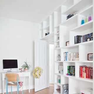 White home office with desk, wooden chair and in-built bookcases