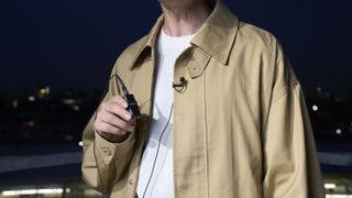 Sony ECM-L1 microphone clipped to a person's jacket with the receiver held in a hand