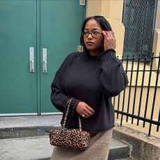 a woman wearing a black sweater, plaid skirt, and black boots