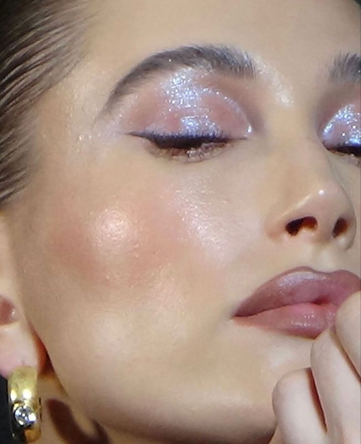Hailey bieber close up image with gold hoop earrings and purple shimmer shadow