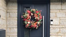 autumn wreath on a front door with red leaves and berries 