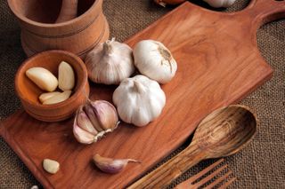 A photo of garlic bulbs on a wooden cutting board