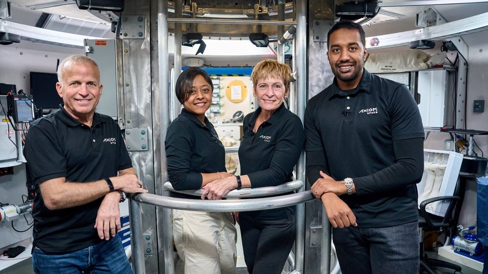 Four private Axiom Space Ax-2 astronauts post inside a space station mockup