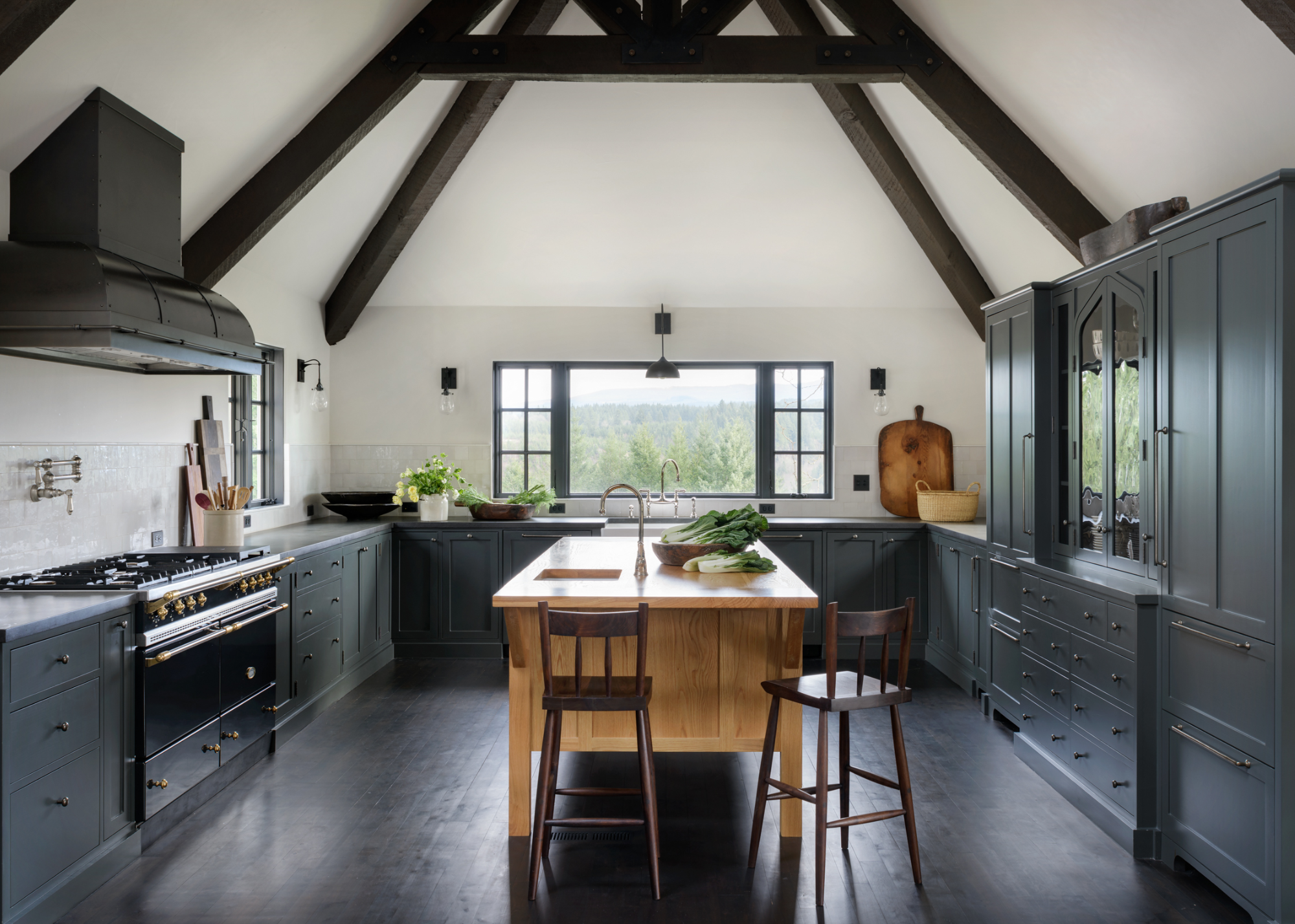 A kitchen in dark tones and dark wood with an oak island in the middle