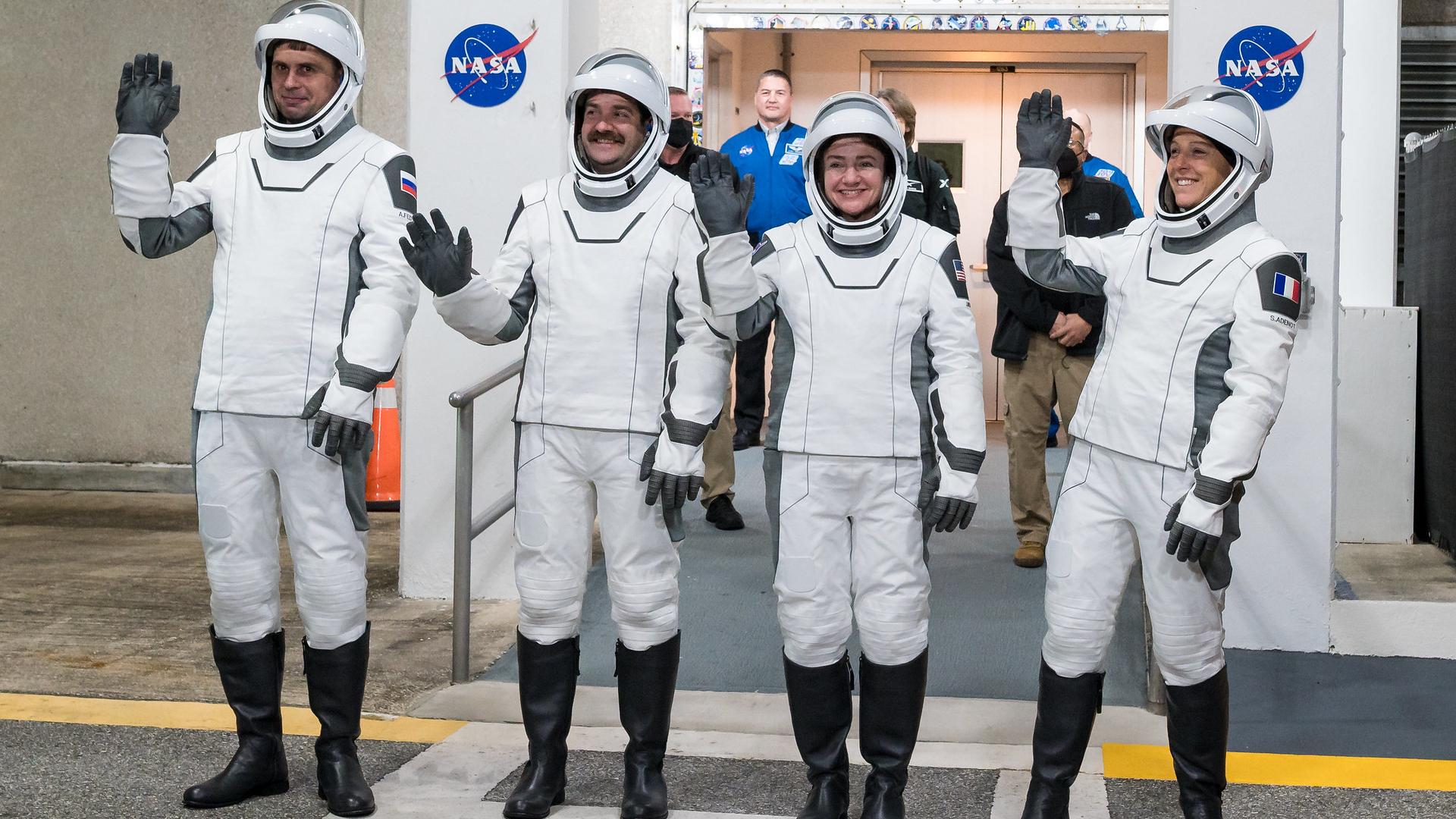 أربعة رواد فضاء من طاقم الطائرة 12، رجلان وامرأتان، يرتدون بدلات الإطلاق والدخول البيضاء من SpaceX.
