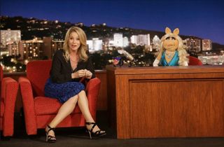 christina applegate sits in a late night chair with miss piggy hosting in The Muppets reboot