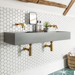 bathroom with white hexagon designed wall grey wash basin mirror with stand and golden tap