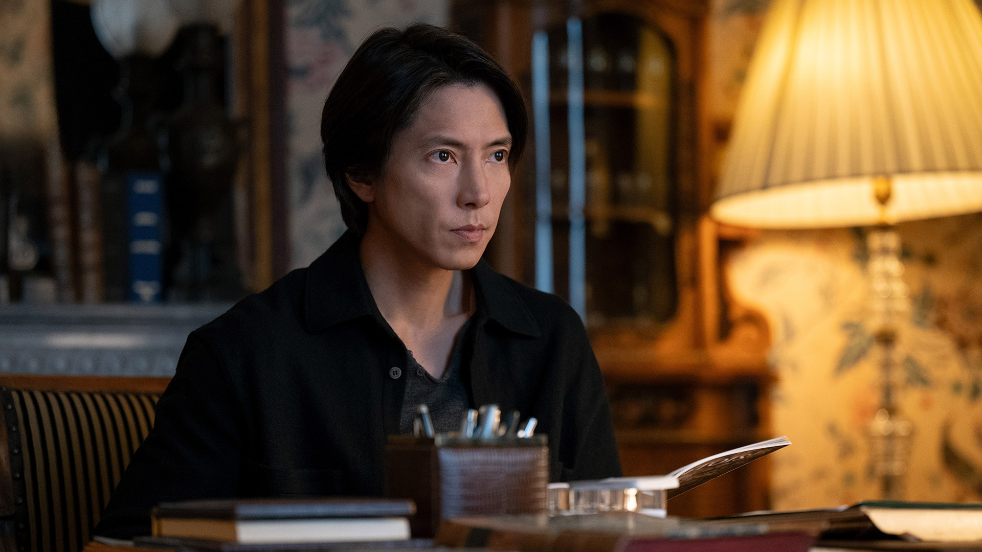 Tomohisa Yamashita sits in front of a desk in Drops of God season 2