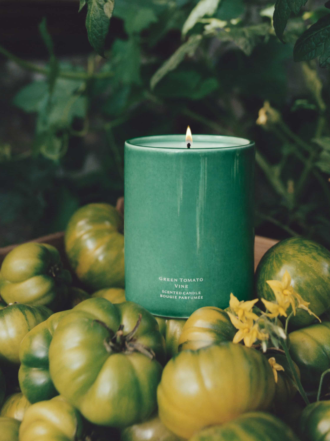 A green ceramic candle from Jo Malone London in a basket of green heirloom tomatoes