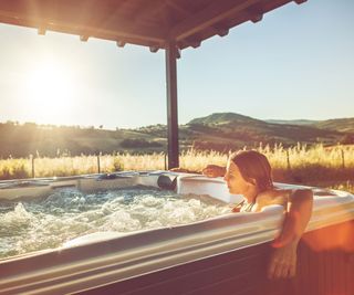 woman relaxing in a hot tub at sunset