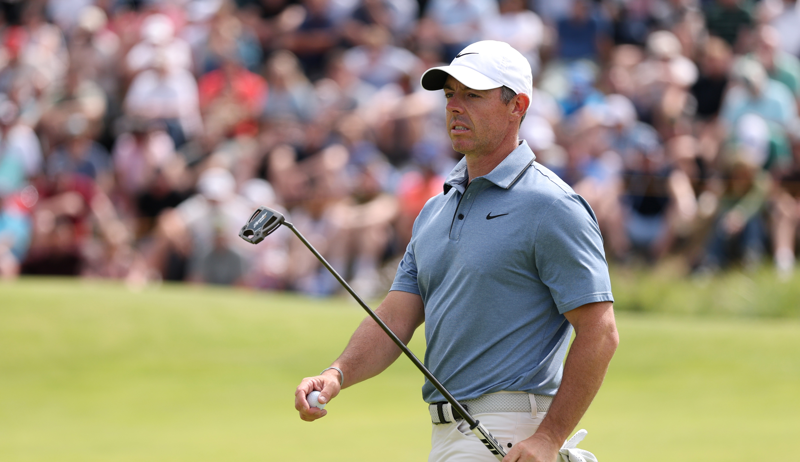Rory McIlroy walks off the green holding a putter