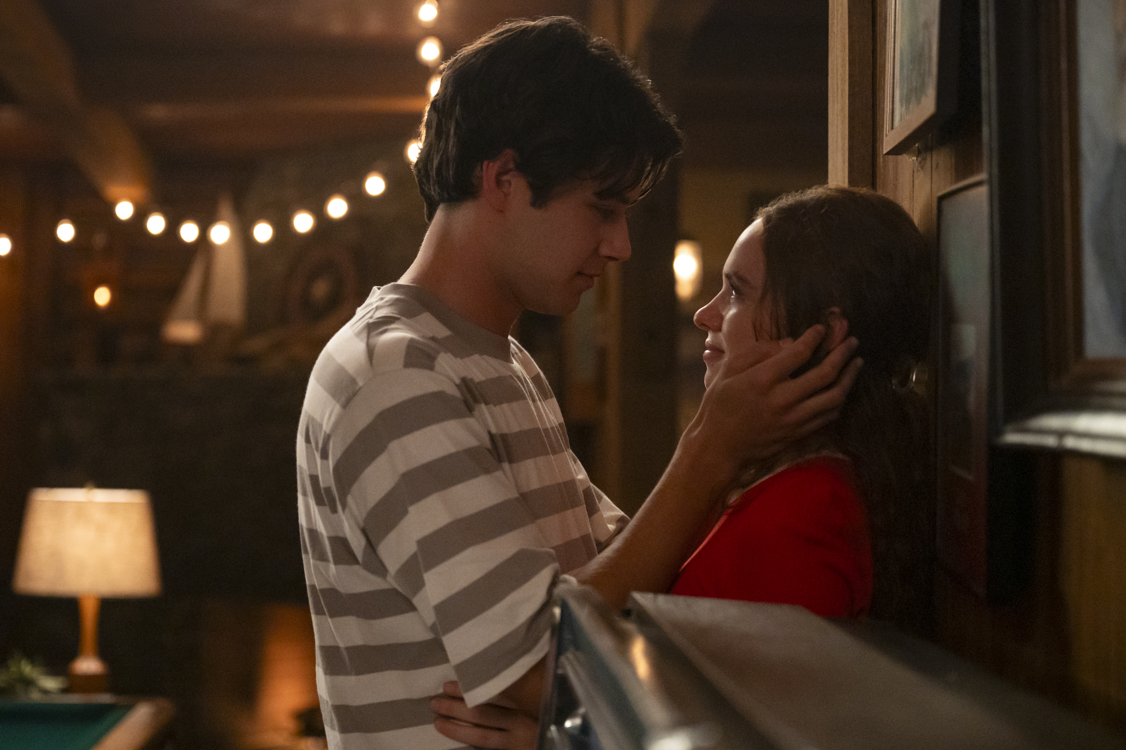 a young man holds a young woman's face in his hands and smiles looking into her eyes in a still from the carley fortune adaptation every year after