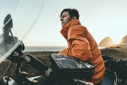 A mature man sits on a large motorcycle and looks into the distance.