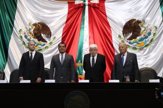 four people in suits stand in front of mexican flags