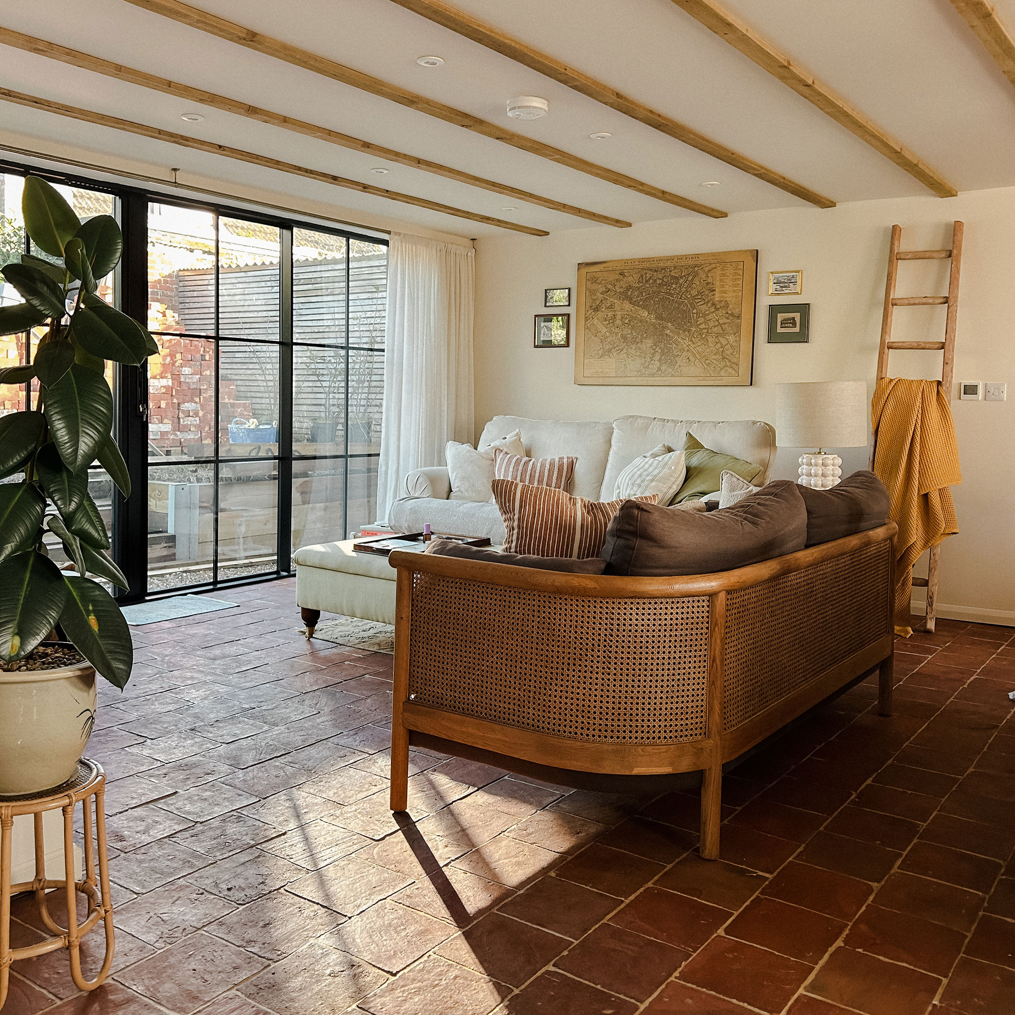 Living room with terracotta floors and cane sofa