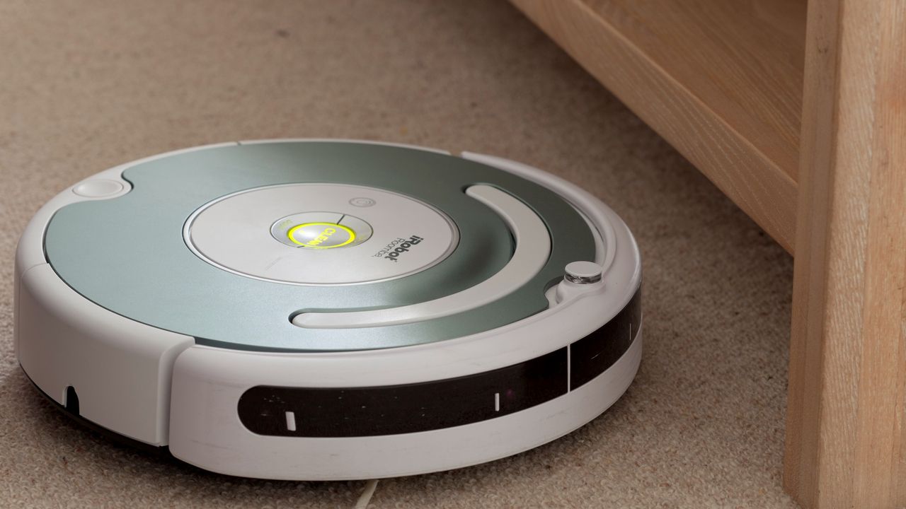 A Roomba robotic vacuum cleaner cleans a carpet.