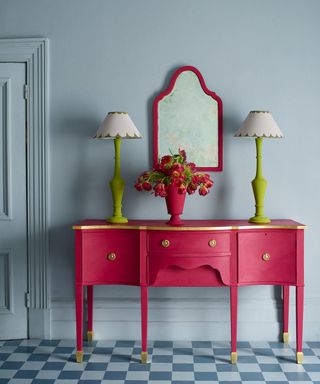 Pink desk and mirror frame, green lamps, blue wall and tiles