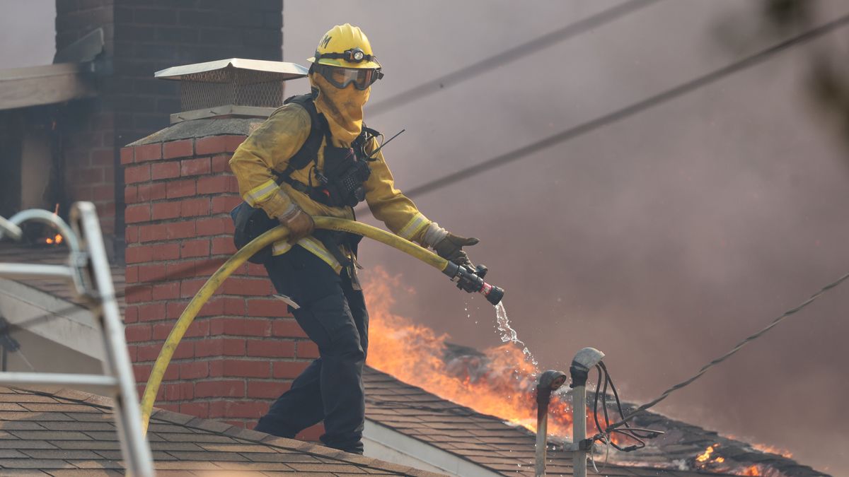 A cropped Cal Fire photo of a firefighter on a rooftop during the 2025 Palisades Fire.