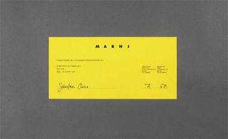 View of ﻿Marni's yellow invitation pictured against a grey background
