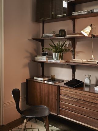 home office with pink walls, mid century furniture and shelving, moveable desk lamp, chair