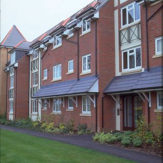 red brick wall mansion with white windows and plants