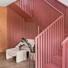 pink staircase on polished concrete flooring with white armchair