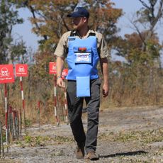 Prince Harry walking through a minefield in Angola with a protective vest