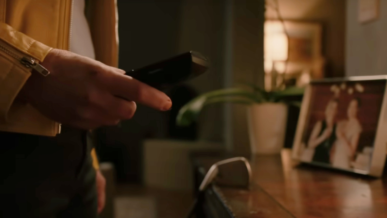 A woman's hand holding a landline phone in Pluribus promo