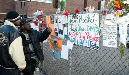 Olel Right (L) and Lionel Frazer (R) look at a wall of flowers and cards outside a music studio in Queens, New York 31 October, 2002 where former Run DMC member Jason Mizell, who was also kno
