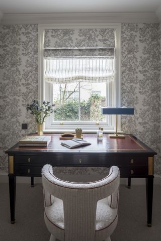 desk in front of a window with roman blinds, lamp and stationery