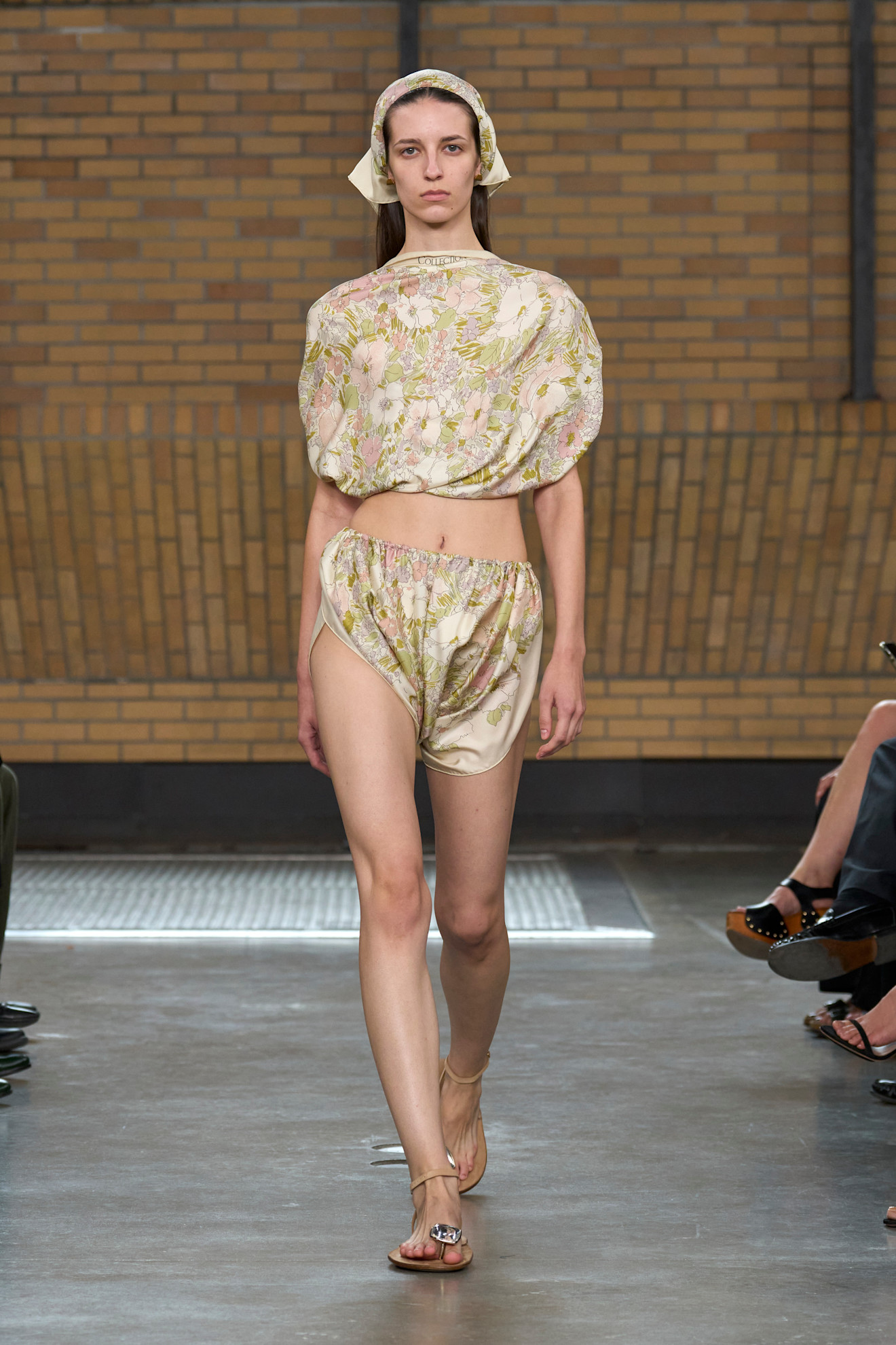 a model wearing a floral top, matching shorts, and brown toe ring sandals