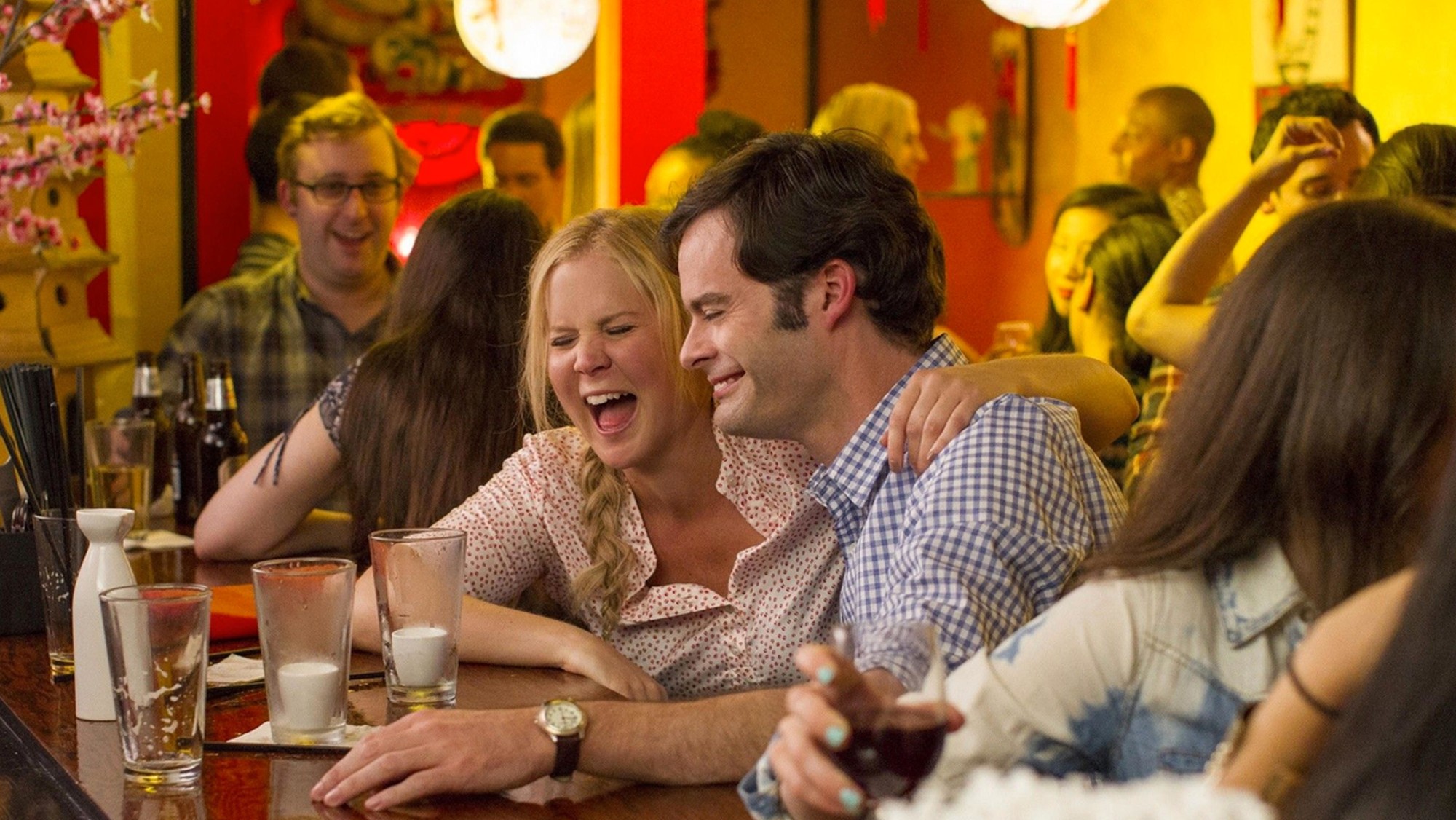 Amy Schumer and Bill Hader laughing in a Chinese restaurant in Trainwreck