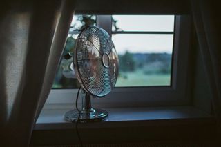 electric fan sitting on an open windowsill on a summer's evening