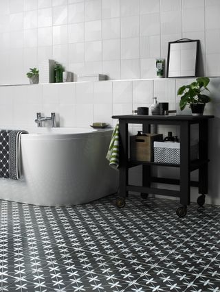 Bathroom with black and white decor: patterned floor, storage unit on wheels