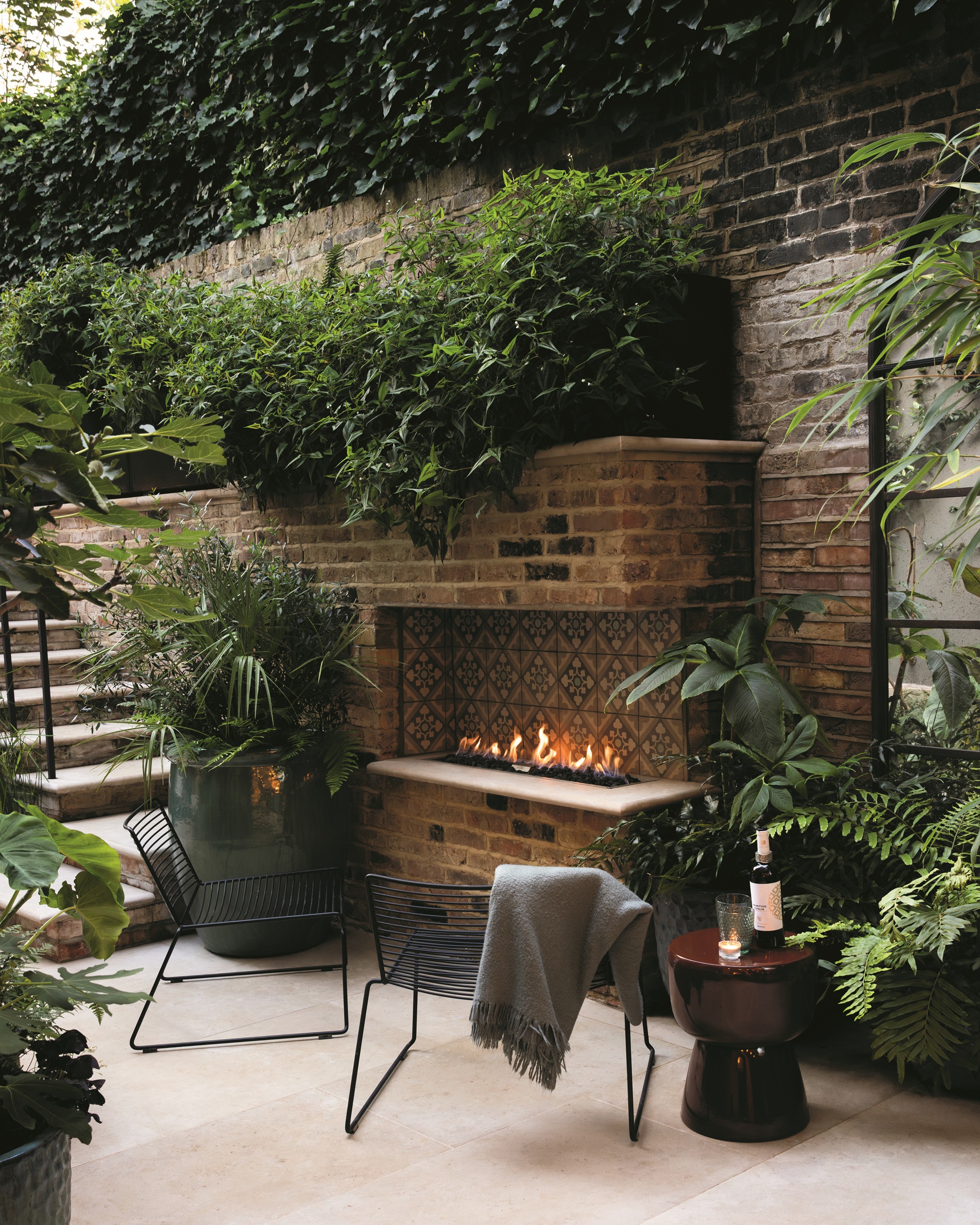 an outdoor fireplace built from brick in a verdant modern garden