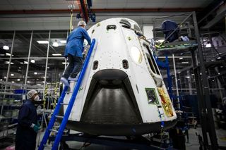 SpaceX technicians work on the Dragon vehicle that will undergo a crucial pad abort test in early 2015.