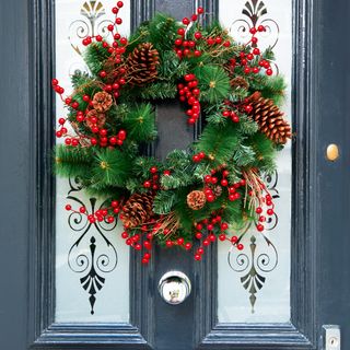 A navy composite front door decorated with a berry Christmas wreath