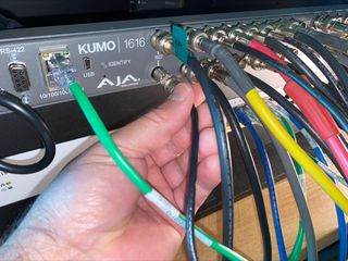 A bunch of mutli-colored cords plug in to a AJA Kumo.