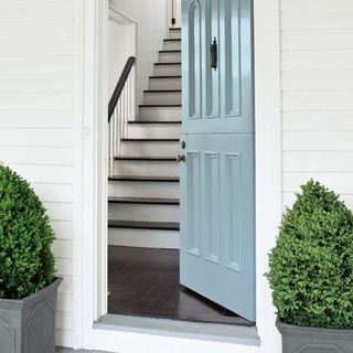 front door colour ideas, pastel blue front door with white painted exterior walls, matching planters, door open, view of staircase