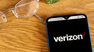 Verizon logo shown on smartphone next to a pair of glasses