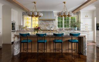 A kitchen with a marble island and unlacquered brass lights