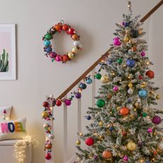 A colourfully decorated Christmas tree at the bottom of a staircase